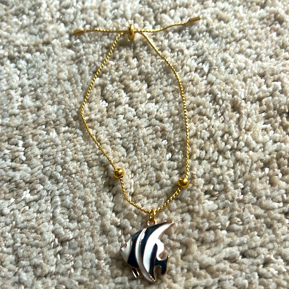 Adjustable gold colored bracelet with fish charm